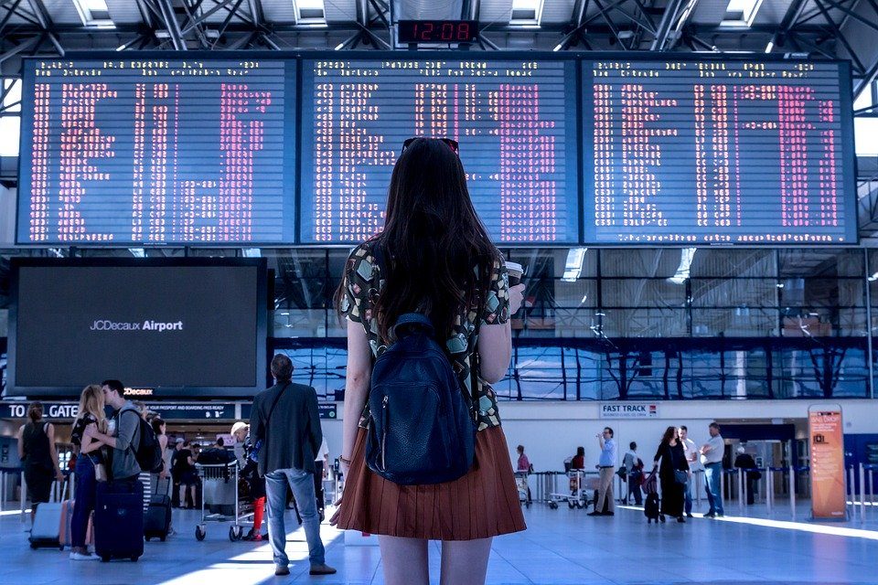 Jeune fiille touriste devant le panneau d'affichage d'un aéroport